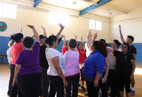 Participantes del programa de prevención de diabetes se reúnen al centro del gimnasio para realizar su porra de motivación diaria. Foto: Joanna Jacobo / El Nuevo Sol 