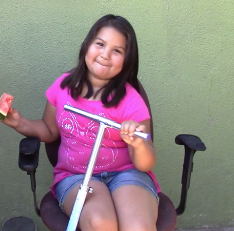 Joanna Sigüenza, de 9 años de edad, come una sandia afuera de su casa. Foto: Natali Castillo / El Nuevo Sol.